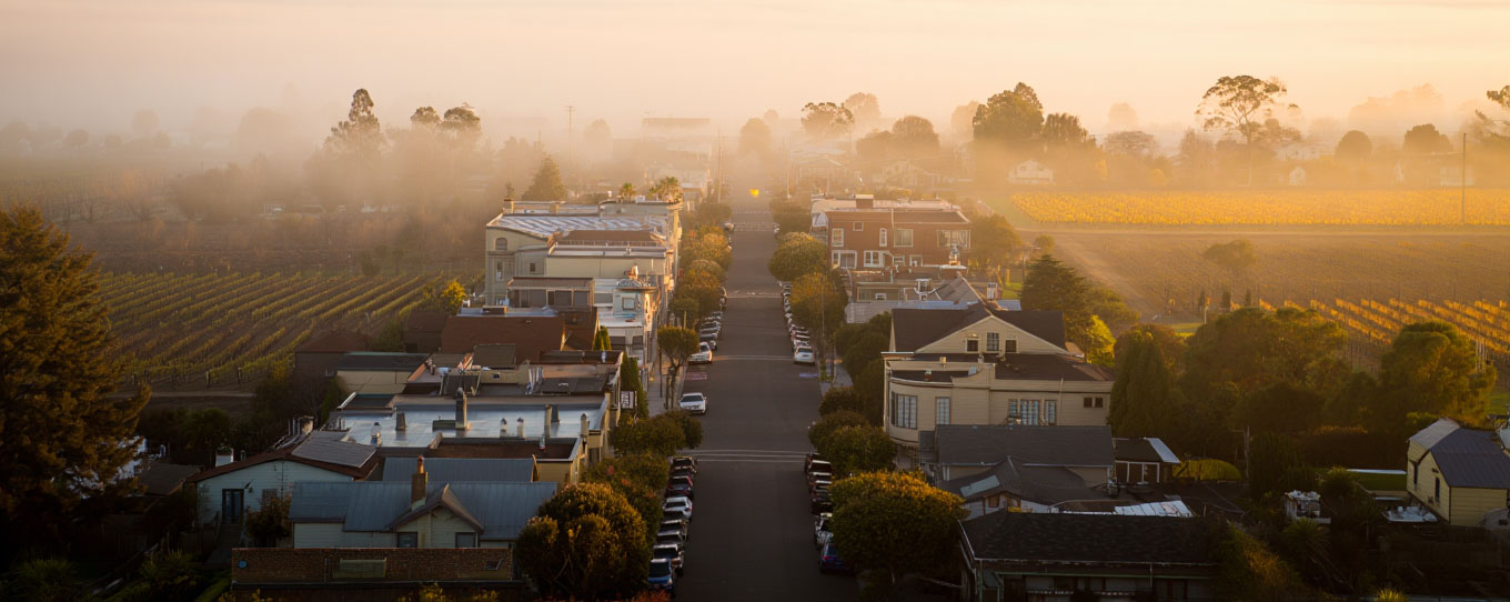Early morning view of downtown Napa with low fog lifting and vineyard hills visible in the distance, showing a calm and affordable base for exploring Napa Valley.