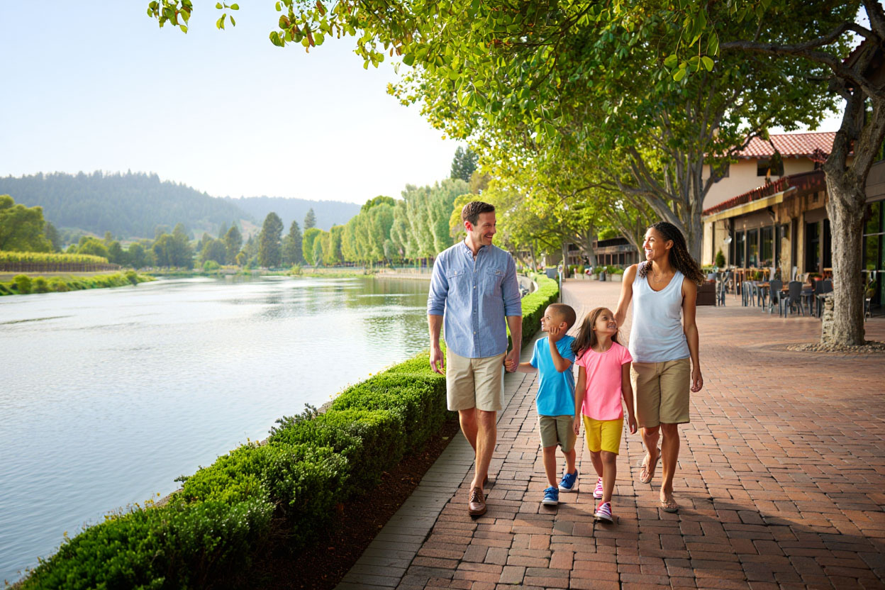 Families walking on open resort lawns at a Napa Valley hotel with vineyard views in the background, illustrating a relaxed family friendly stay.