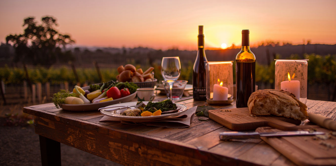 Outdoor farm to table dining experience in Napa Valley with seasonal dishes, vineyard views, and warm evening light