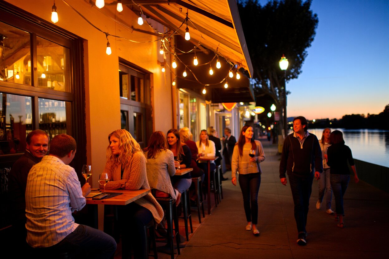 Downtown Napa Valley at night with softly lit bars, music venues, and people walking near the Napa River during an evening out.