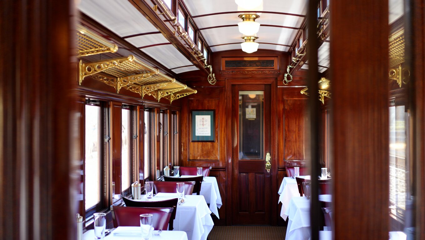 Interior of a historic Pullman railcar on the Napa Valley Wine Train featuring polished wood, brass details, and natural light from vineyard-facing windows.