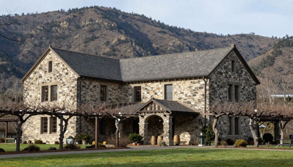  Historic stone winery building on Mount Veeder in Napa Valley surrounded by winter vineyard rows showing thick masonry walls and mountain-integrated design.