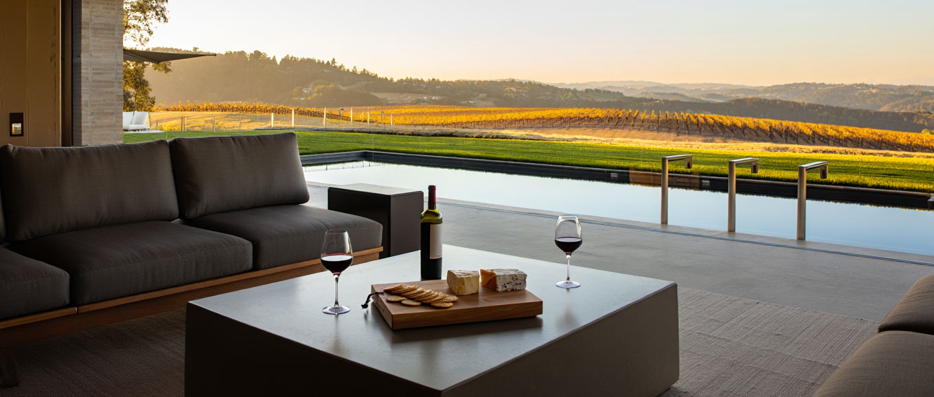 Outdoor patio at a Napa Valley vacation rental with wine glasses on a table and vineyard views in the late afternoon light.