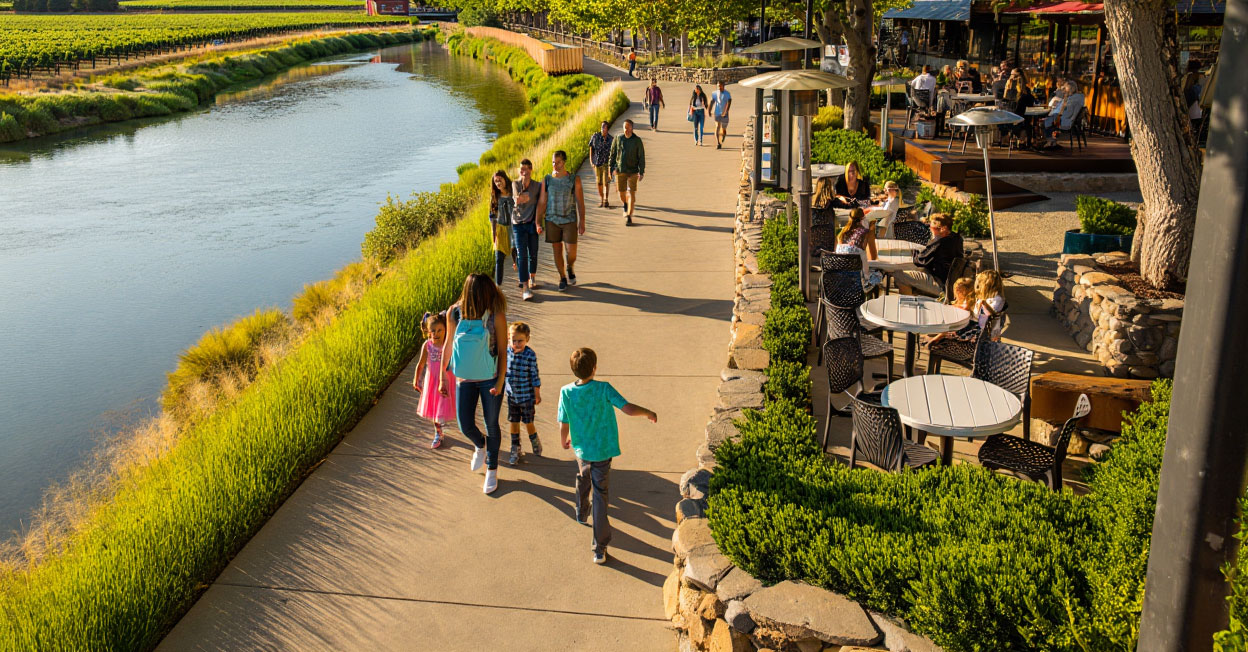 Family friendly hotel pool in Napa Valley with children swimming and parents relaxing nearby, set against vineyard and hillside scenery.