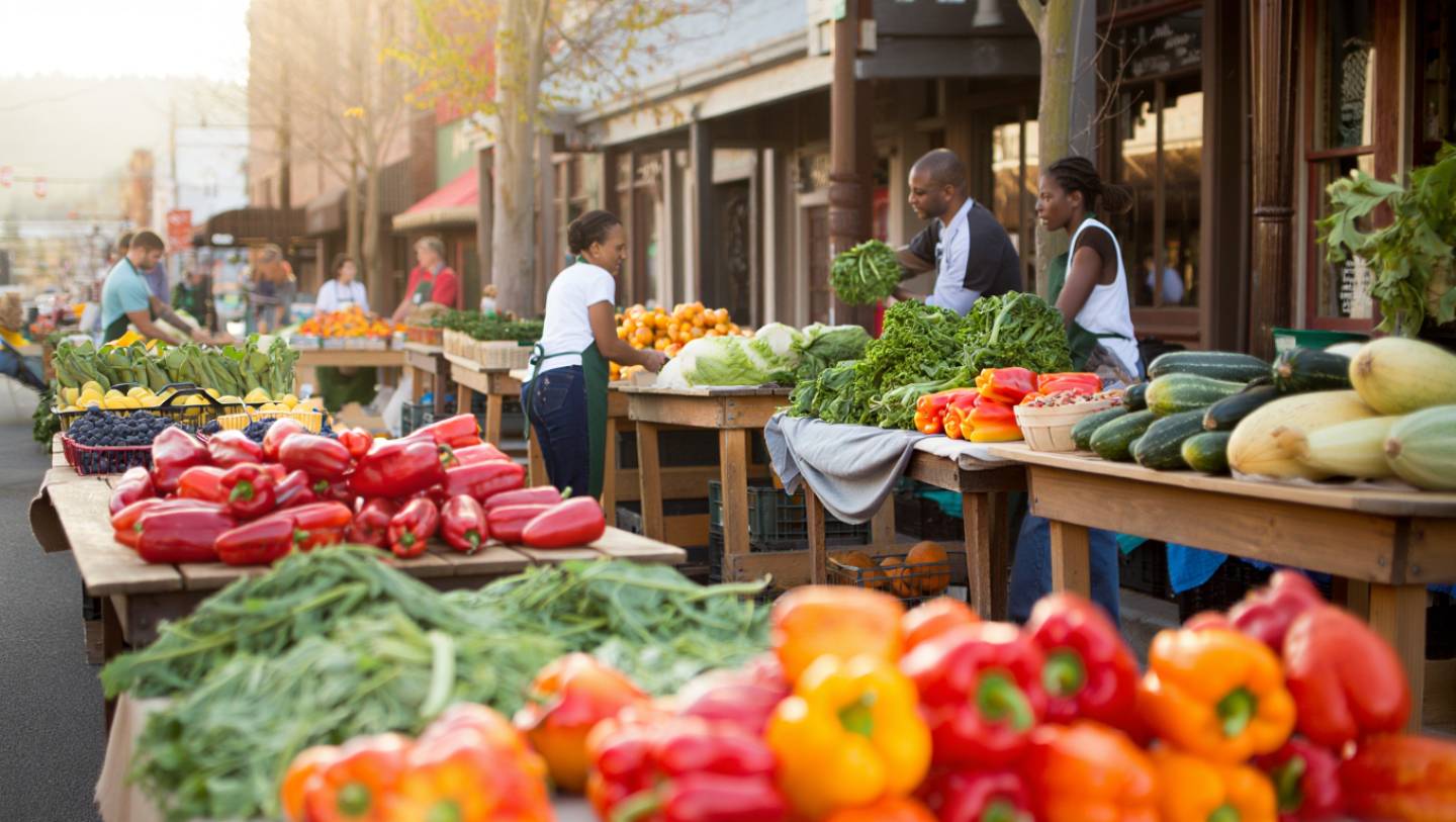Early morning farmers market in Napa Valley with tables of fresh seasonal produce and growers preparing for the day.