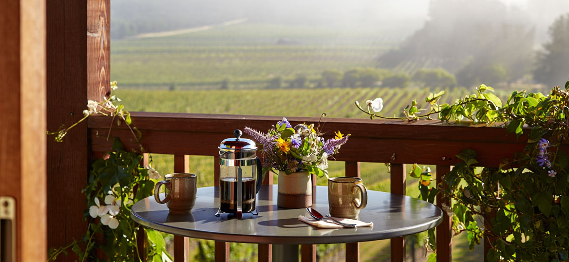 Golden hour view from a Napa Valley hotel overlooking vineyard rows and the Mayacamas mountains, ideal for first-time visitors choosing where to stay.