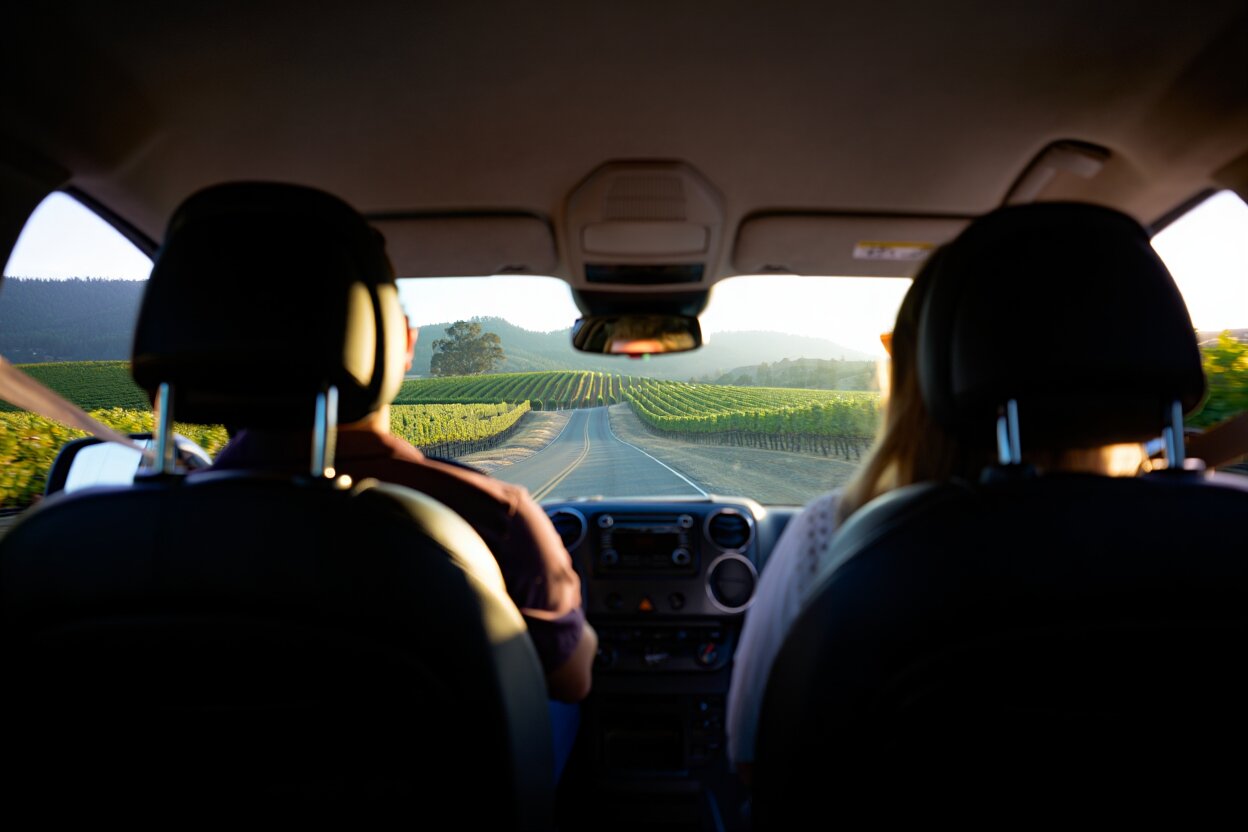 View from inside a private wine tour vehicle driving along Silverado Trail with Napa Valley vineyards visible through the windshield.