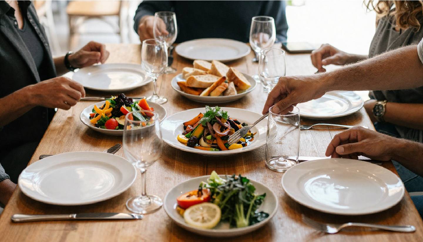 Shared seasonal dishes on a Napa Valley restaurant table, showing a relaxed long lunch experience focused on food and conversation rather than wine tastings.