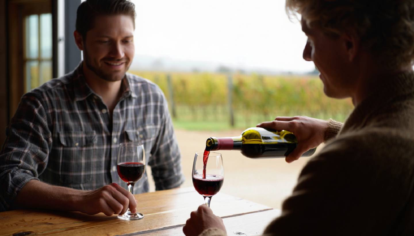 Small appointment only winery tasting in Napa Valley with a few guests, wine glasses on a table, and vineyard views emphasizing a calm, uncrowded experience.