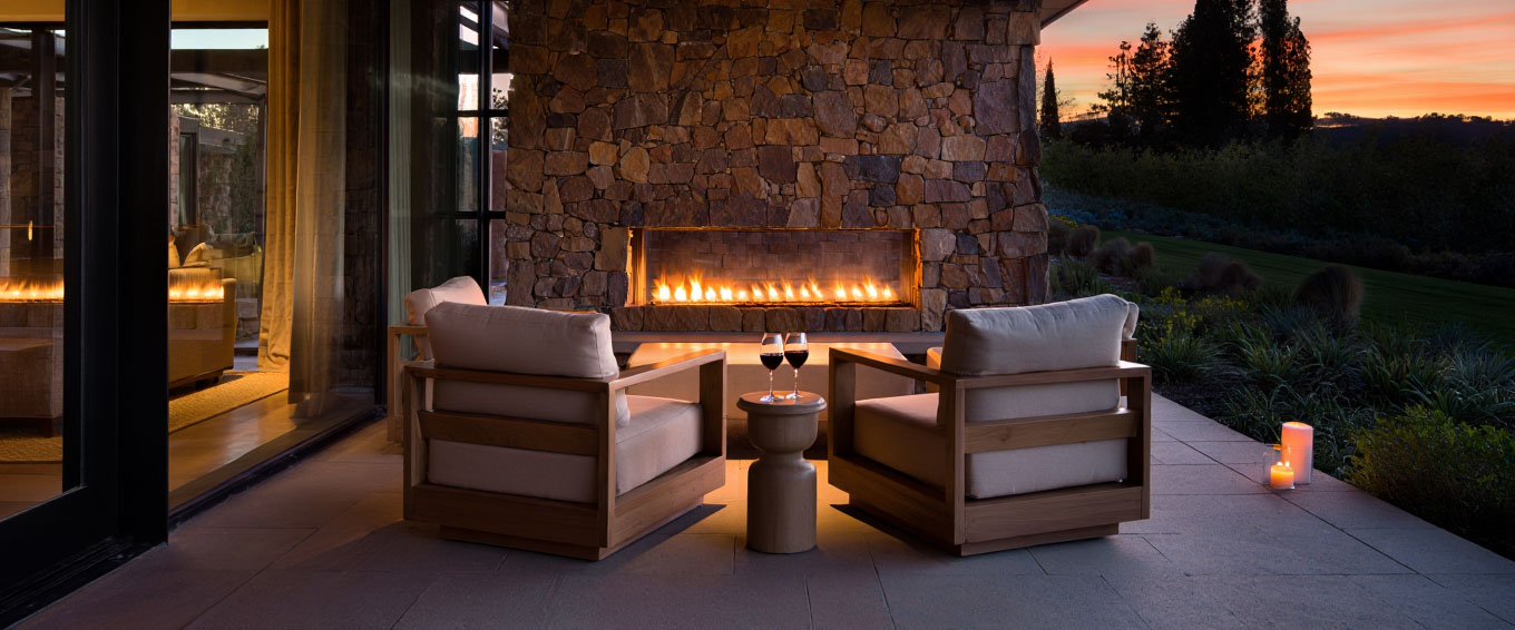 Private patio at a romantic Napa Valley hotel with outdoor fireplace and wine glasses, creating an intimate evening atmosphere.