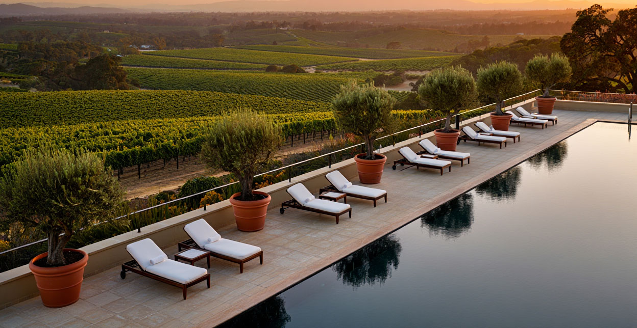Golden hour vineyard view from a spa resort terrace in Rutherford, showing vine rows across the Napa Valley floor and a calm evening setting.