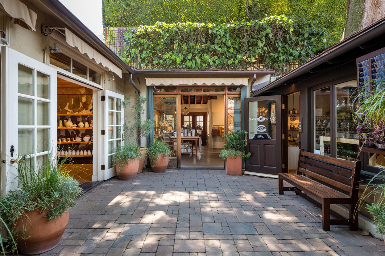 Yountville village shopping area with small boutiques and design focused storefronts. Narrow sidewalks, planters, and subtle architectural details. No crowds or identifiable faces. Boutique shopping area in Yountville Napa Valley with small storefronts and a quiet village setting.