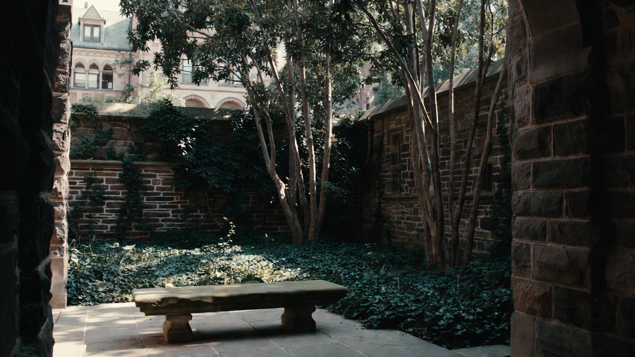 An empty stone bench in a shaded, quiet courtyard at the CIA Greystone in St. Helena, featuring historic stone masonry walls and soft sunlight filtering through garden foliage.