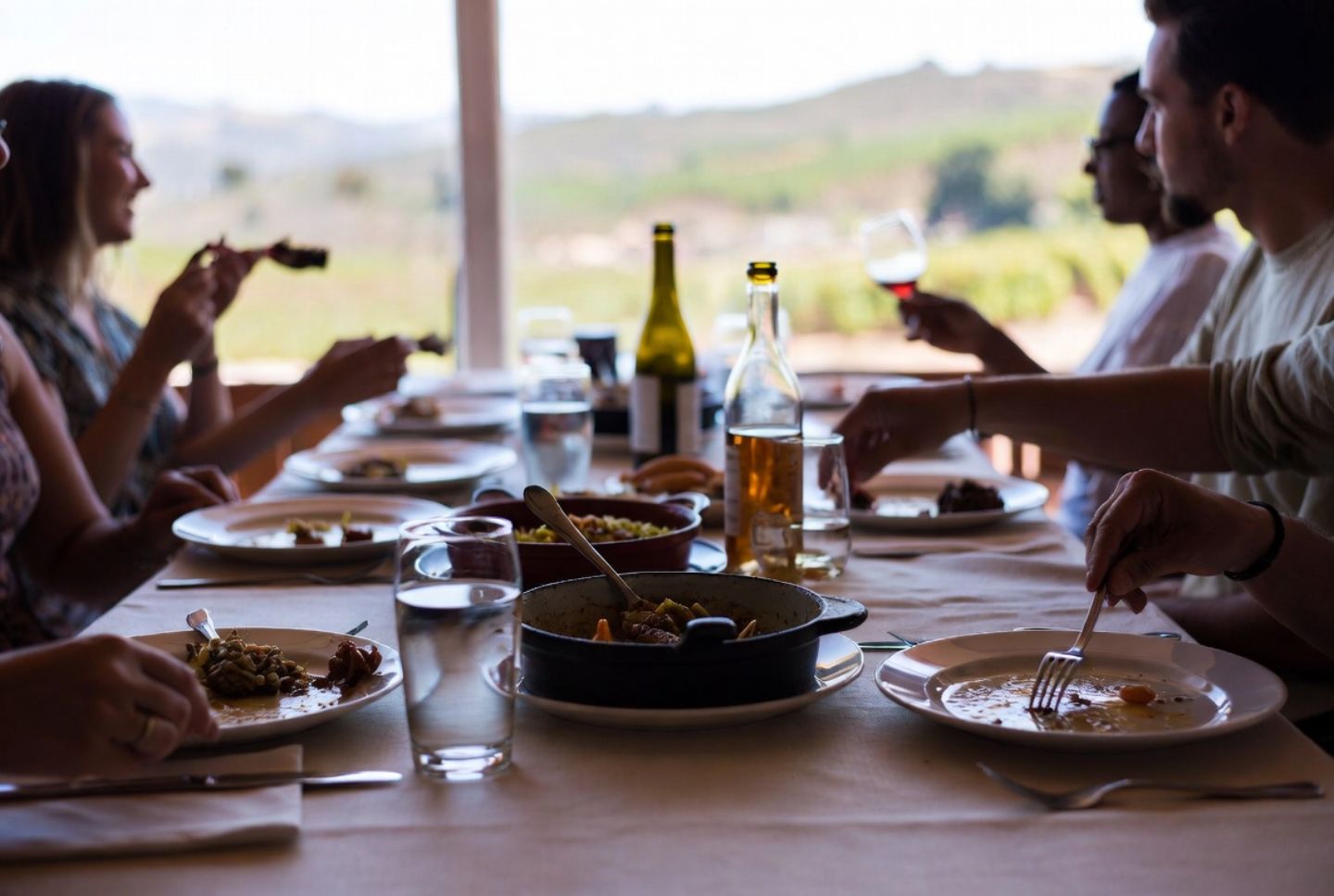 Long lunch table in Napa Valley with shared plates and an open bottle, representing food first wine travel experiences popular with San Jose and South Bay visitors.