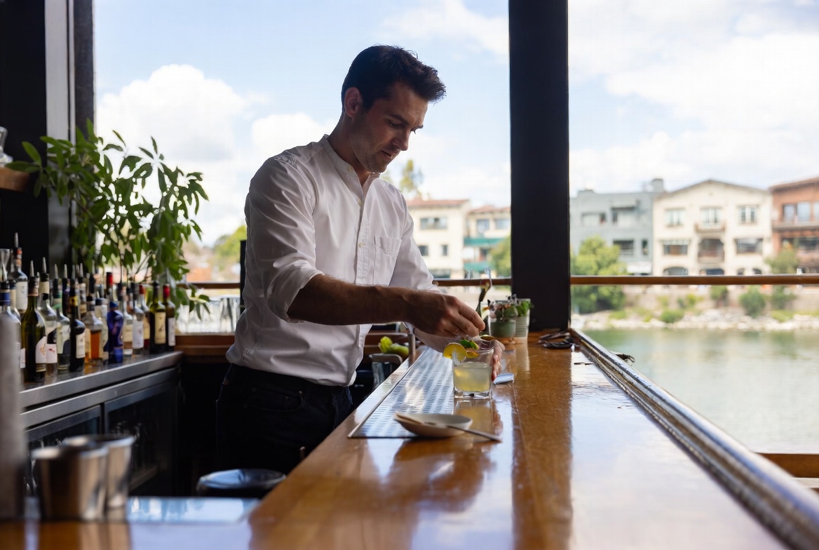 Bartender preparing a farm to glass cocktail with fresh citrus and herbs at a bar in downtown Napa overlooking the Napa River