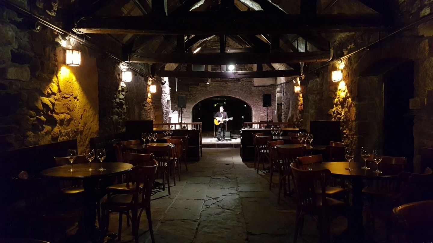 Intimate jazz performance inside a historic Napa Valley stone building, with low lighting, close seating, and a musician performing on a small stage.