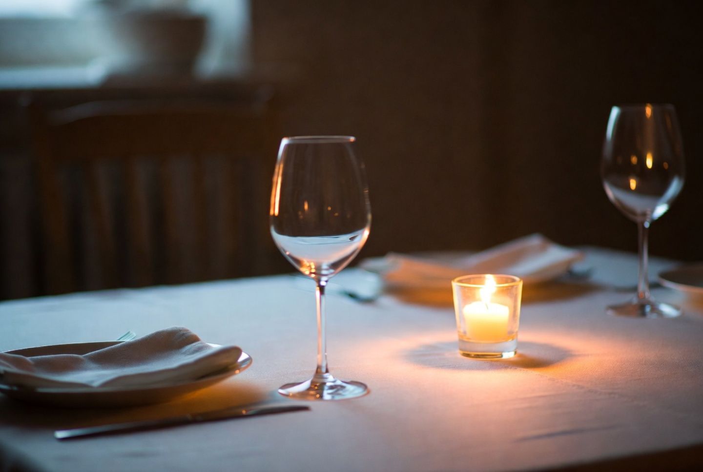 Candlelit table setting in a Napa Valley restaurant with wine glasses and soft shadows, emphasizing an intimate and romantic dining experience.