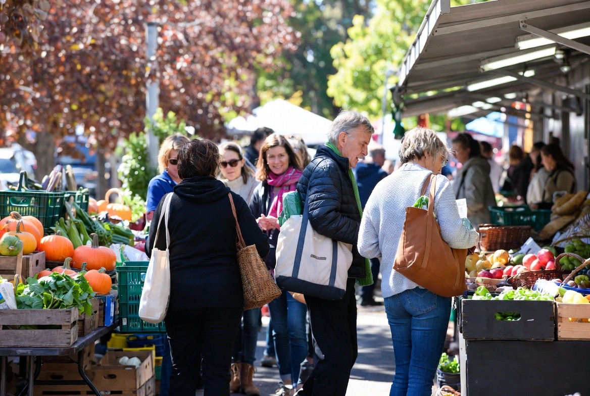 Friends shopping together at a Napa Valley market in late fall, selecting seasonal ingredients for a Friendsgiving weekend in wine country.