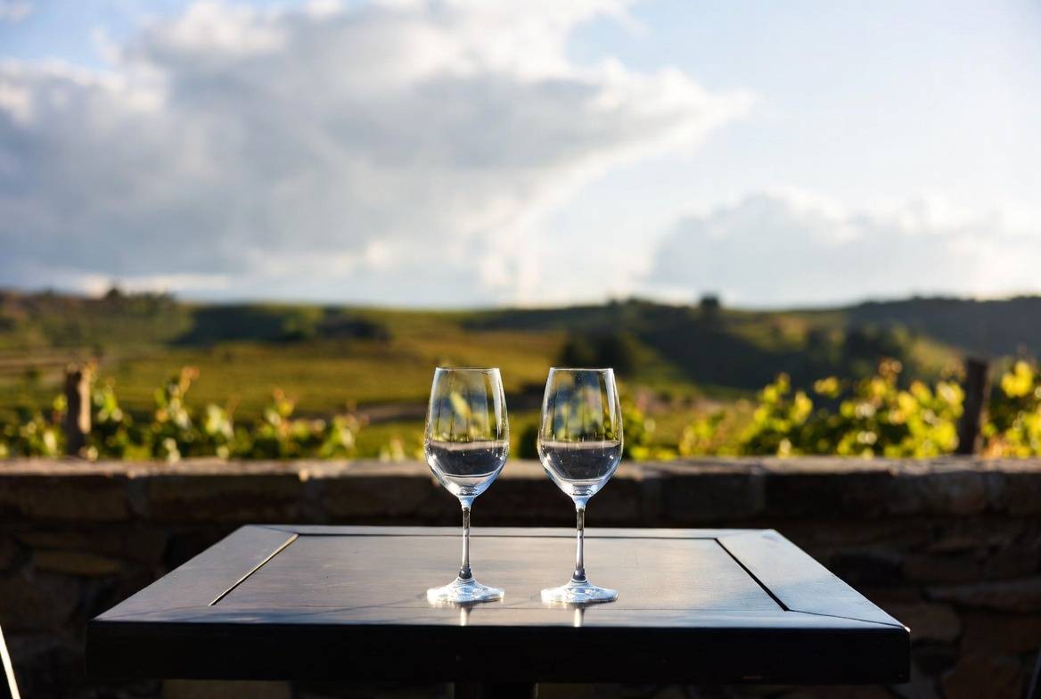 Quiet winery terrace in Napa Valley with two wine glasses and vineyard views, ideal for a private anniversary tasting experience.
