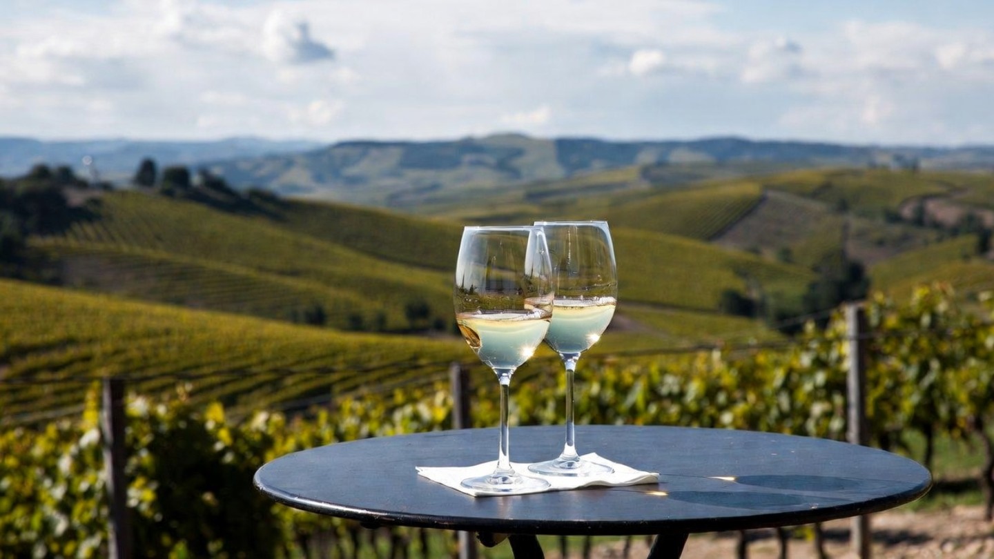 Two wine glasses on a vineyard terrace in Napa Valley with rolling hills in the background, representing a quiet moment shared by a newly engaged couple.