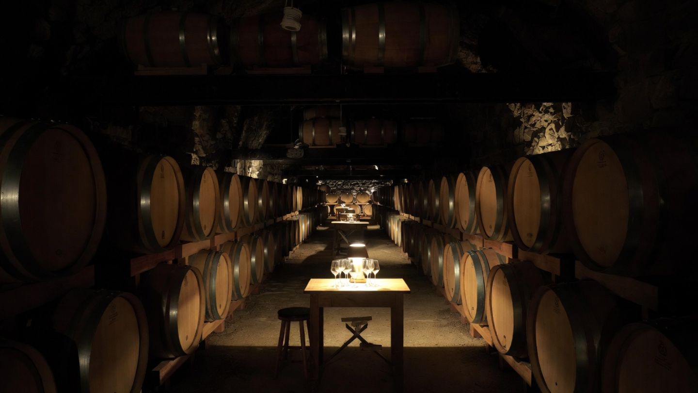 Interior Napa Valley wine cellar with barrel rows and tasting table, highlighting a warm indoor experience during rainy weather.