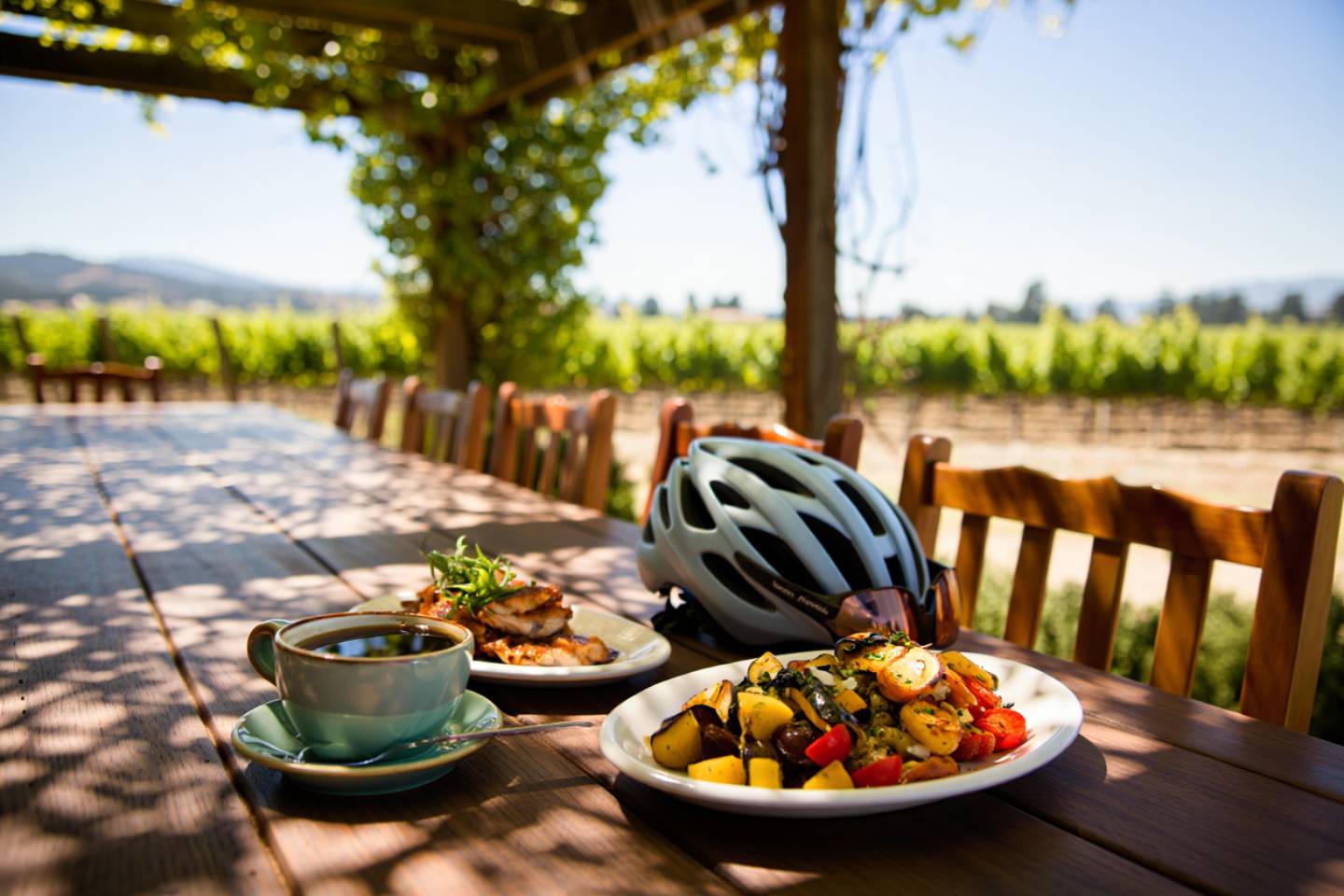 Farm to table lunch on a vineyard patio in St. Helena Napa Valley after a cycling ride with helmet and water bottle on the table.